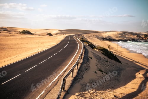 Preview: Long black asphalt road with desert and beach