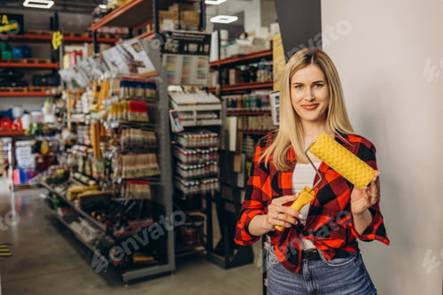 Preview: Young independent woman buying paint roller and tools for house decoration in hardware store