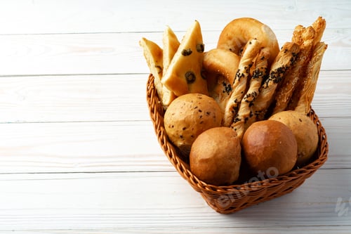 Preview: Bakery products in straw bread basket on wooden table