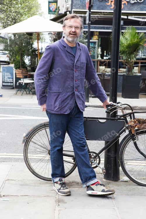 Preview: Man pausing with his bike on a city street