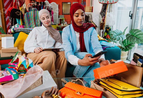 Preview: Muslim women friends enjoying online shopping unboxing fashion purchases at home