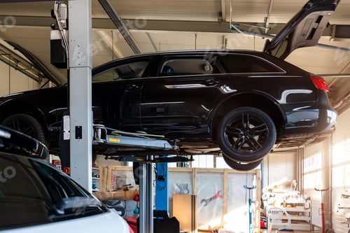 Preview: Car service center. Bottom behind pov vehicle raised on lift technician worker perform diagnosticas