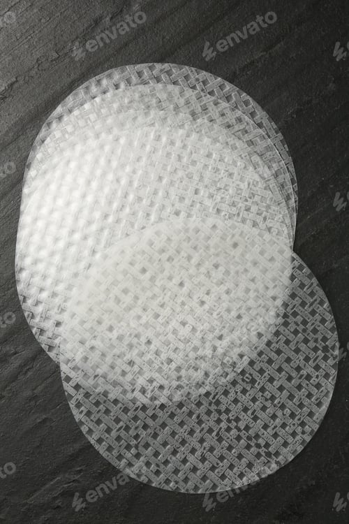 Preview: Edible rice paper sheets on dark textured table, flat lay