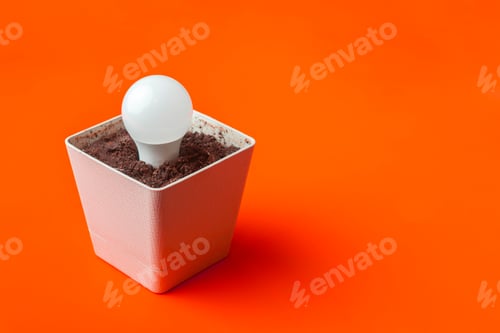 Preview: creative idea of the light bulb in the pot with soil with copy space on color surface