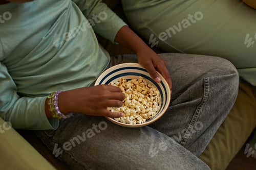 Preview: Black Child Eating Popcorn While Sitting Indoors during Leisure Activity