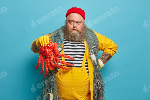 Preview: Photo of serious sailor works on ship, holds big octopus, carries fishing net, has sailing expeditio