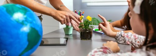 Preview: Teacher and young students pointing to pansy plant in ecology classroom