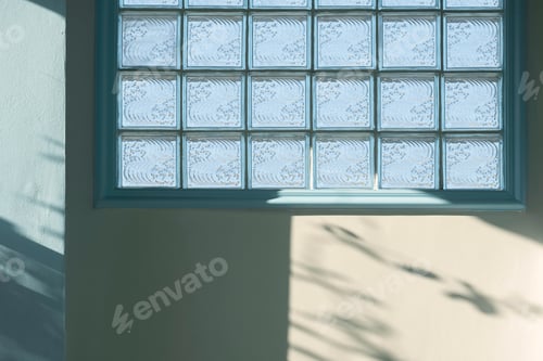 Preview: Sunlight and shadow on surface of glass brick block on white and blue concrete wall inside of home