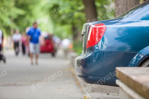 Preview: Car parked in pedestrian zone under trees on city street with walking people on summer day