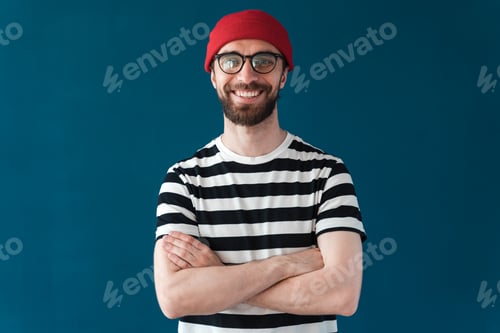 Preview: Smiling man in glasses and red hat on a blue background. Brunette man isolated on blue