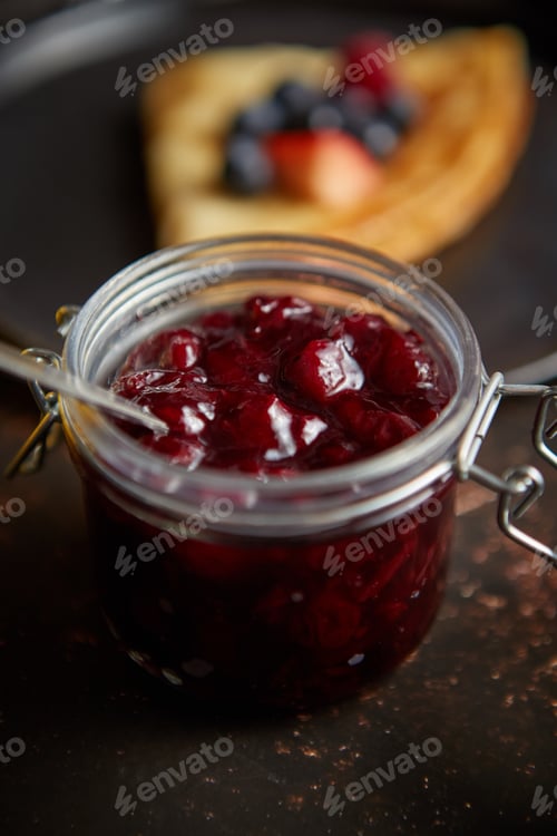 Preview: Close up on jar filled with fresh cherry marmalade placed on dark rusty table