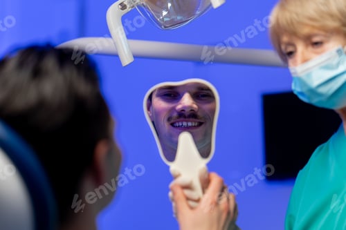 Preview: close-up in a dental clinic the dentist shows the result to the patient through the mirror
