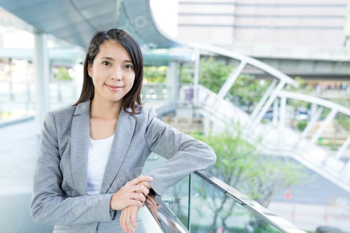 Confident Woman in Business Attire Leans on Railing