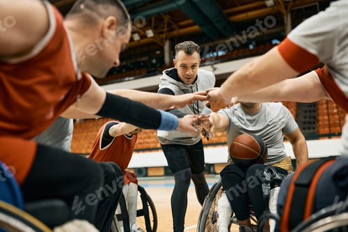 Preview: Wheelchair basketball team and their coach gathering hands in unity before the match.