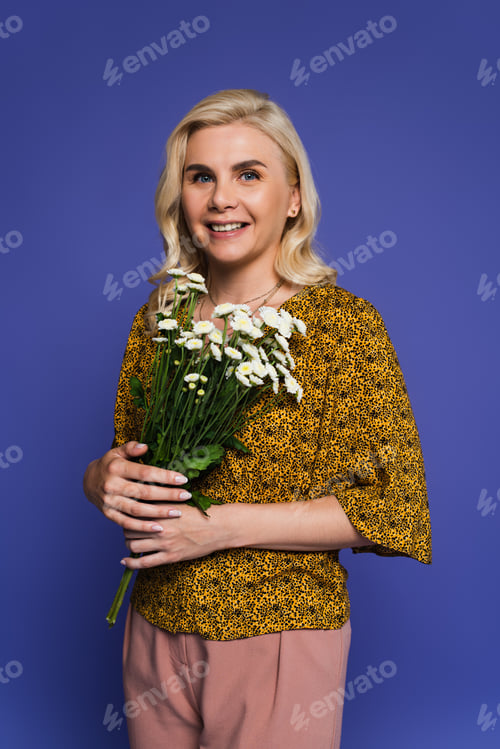 Preview: happy woman in blouse holding bouquet of white flowers with green leaves isolated on violet