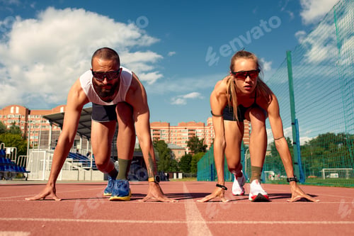Preview: Young sporty woman and man are ready to run on racetrack. Fit well formed people are at large nice
