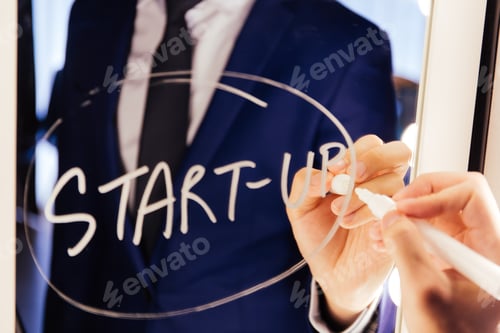 Preview: Smart business man writing the word Start-up on the mirror board