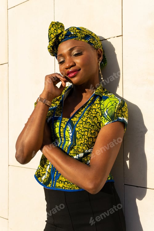 Preview: Stylish ethnic woman in ornamental wear standing dreamily on street