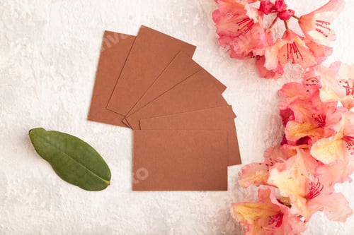 Preview: Brown business card with pink azalea flowers on gray concrete background. top view, copy space.