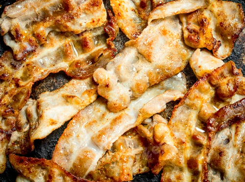 Preview: Fried bacon in a frying pan.