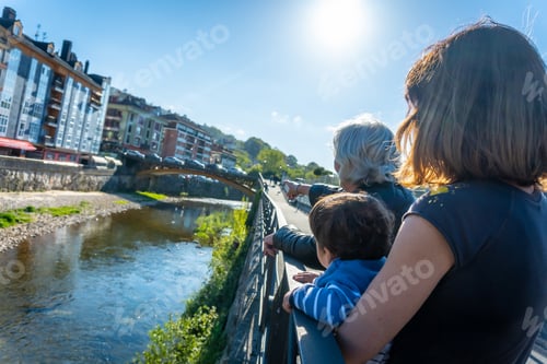 Preview: A family looking at the Sella river in the town of Cangas de Onis. Asturias. Spain