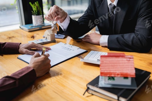 Preview: Real estate agent giving key from new house to young man in office