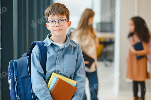 Preview: Happy cute clever boy in glasses with school bag and book in his hand