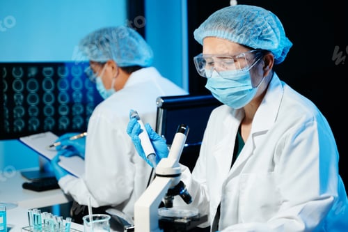 Preview: Medical scientists working in laboratory using microscope and analyzing brain scan data