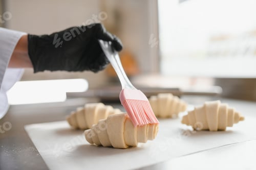 Preview: Baker glazing croissants with silicone brush in bakery