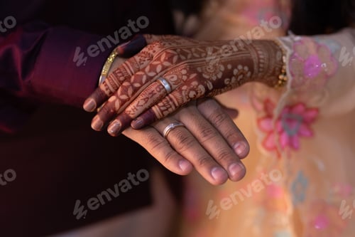 Preview: Happy wedding couple holding hands. The woman's hand with intricate henna.