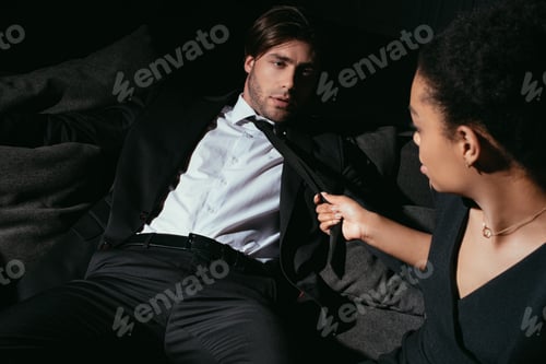 Preview: young multiracial sexy couple in black clothing on sofa
