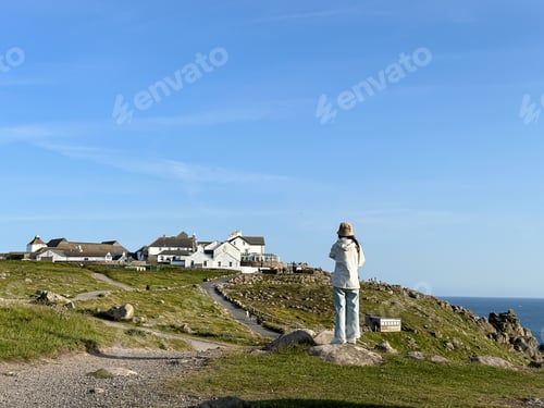Preview: Land's end Hotel view and Cornwall coastline in England, UK. Young woman making photo of view, photo