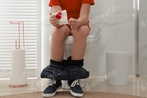 Preview: Boy holding toilet paper with blood stain in rest room, closeup. Hemorrhoid concept