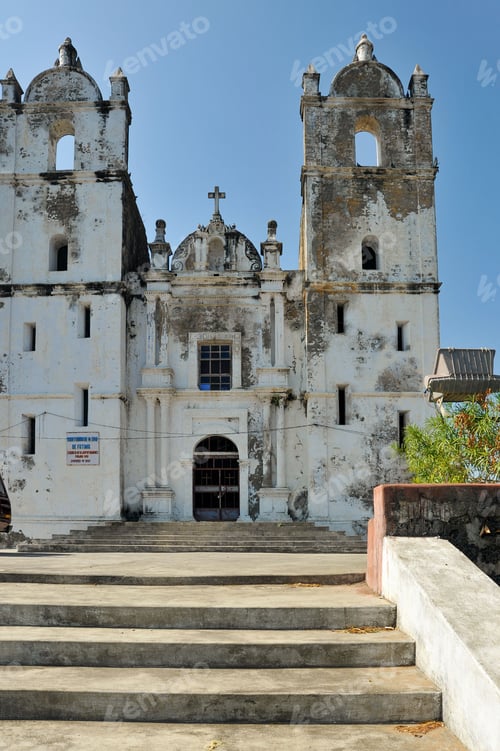 Preview: Vertical shot of stairs leading to an old Portuguese Church against a blue sky on a sunny day