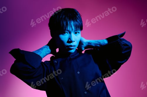 Preview: Young handsome asian male chef showcasing unique style in vibrant lighting during a photoshoot