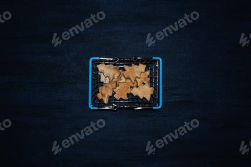 Preview: Modern flat lay with cookies Christmas tree shape in shopping cart on dark blue background. Hard
