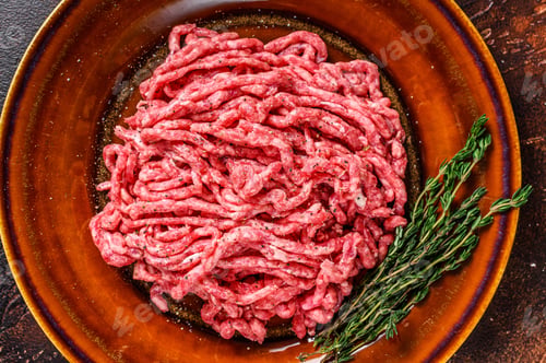 Preview: Raw mince angus wagyu beef, ground meat with herbs on a plate. Dark background. Top view