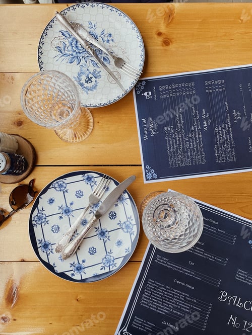 Preview: People having a lunch at the restaurant.Plates, porks and knives on table at the top.Restaurant menu