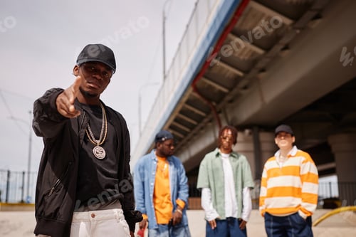 Preview: Young African American man in black cap and bomber jacket pointing at you