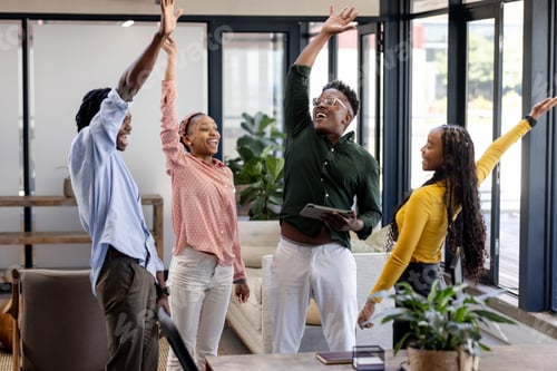 Preview: African American colleagues celebrating success with high fives in modern office