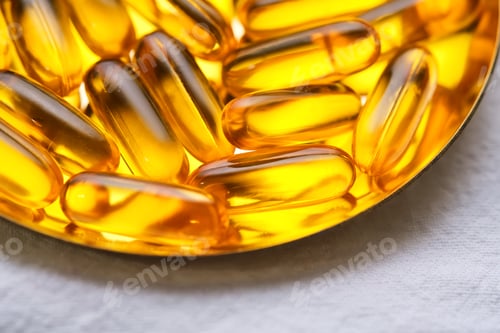 Preview: Yellow capsules with Omega-3 fish oil on a golden tray.