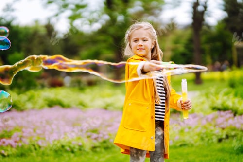 Preview: Cute little girl in autumn on walk blowing soap bubbles. Childhood, active rest, lifestyle concept.