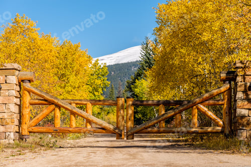 Preview: Rustic gate made of logs on unpaved road