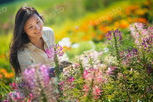 Preview: A young woman in a garden surrounding by flowers.
