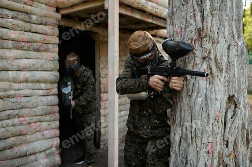 Preview: Paintball players in uniform shoots with guns