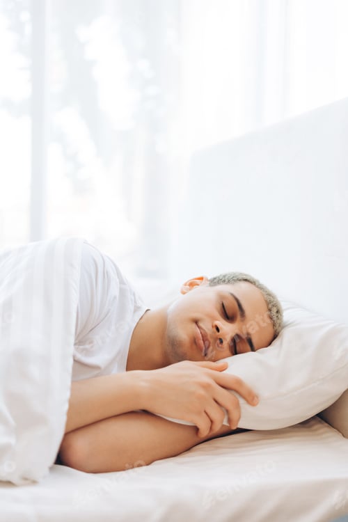 Preview: Positive attractive male dreaming with a smile on his face while lying on a soft pillow