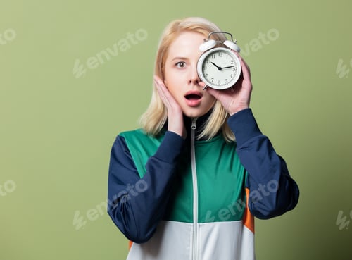 Preview: Beautiful blonde woman in 90s sport suit with alarm clock