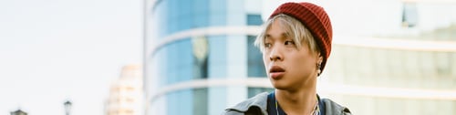 Preview: Asian boy wearing hat looking aside at city street