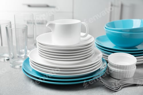 Preview: Set of clean dishes and cutlery on table in kitchen
