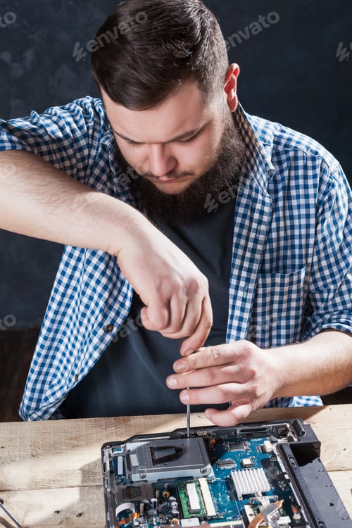 Man Repairing a Computer on a Wooden Table